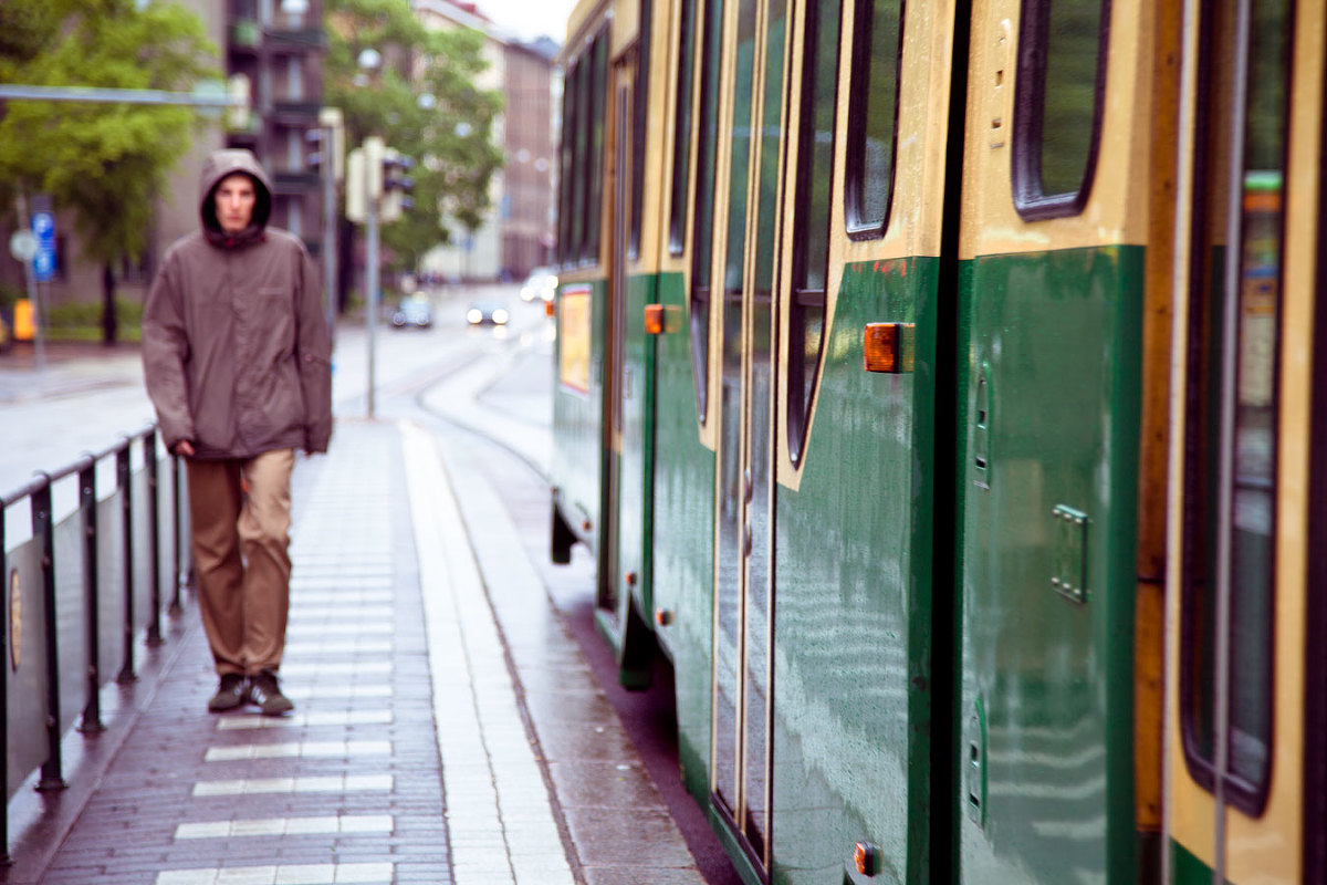 Summer Day in Helsinki - man walks beside a tram the streets glisten with rain